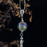 Purple pinkish silver glass pendant with chain tassel on long chain.