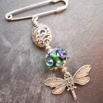 Brooch with dragonfly pendant and green bead with silver glass ornaments