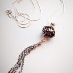 Dark amber color pendant with silver glass ornaments and chain tassel on a long chain