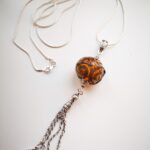 Light amber color pendant with silver glass ornaments and chain tassel on a long chain